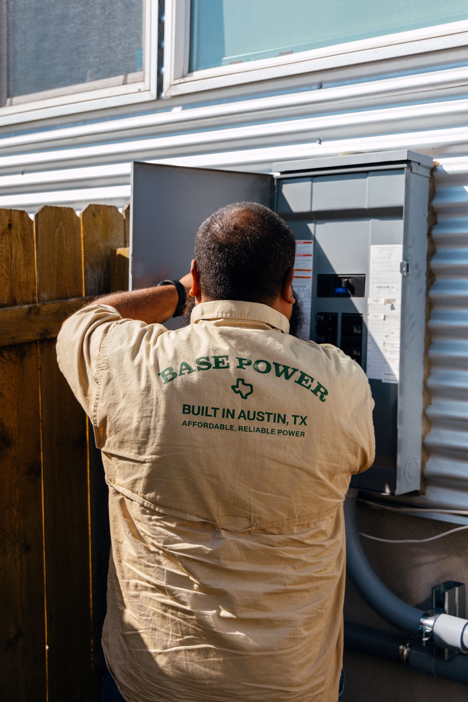 A Base technician wiring an electrical panel at the side of a home