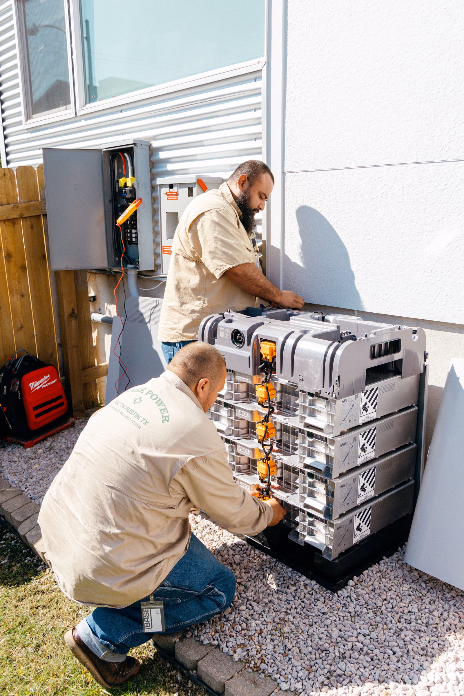 Two Base electricians assembling a battery's stacked modules on site