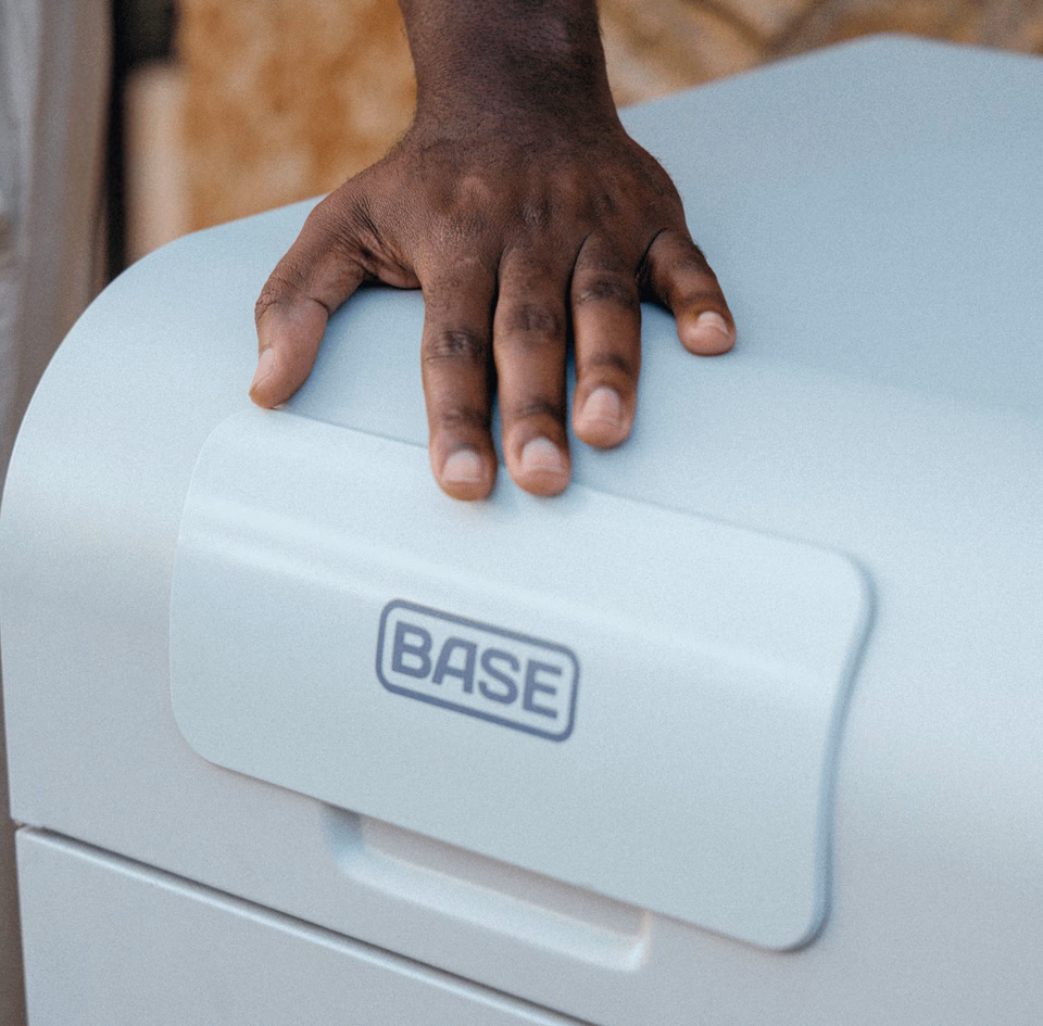 A hand resting on the lid of a Base Core battery above its Base badge
