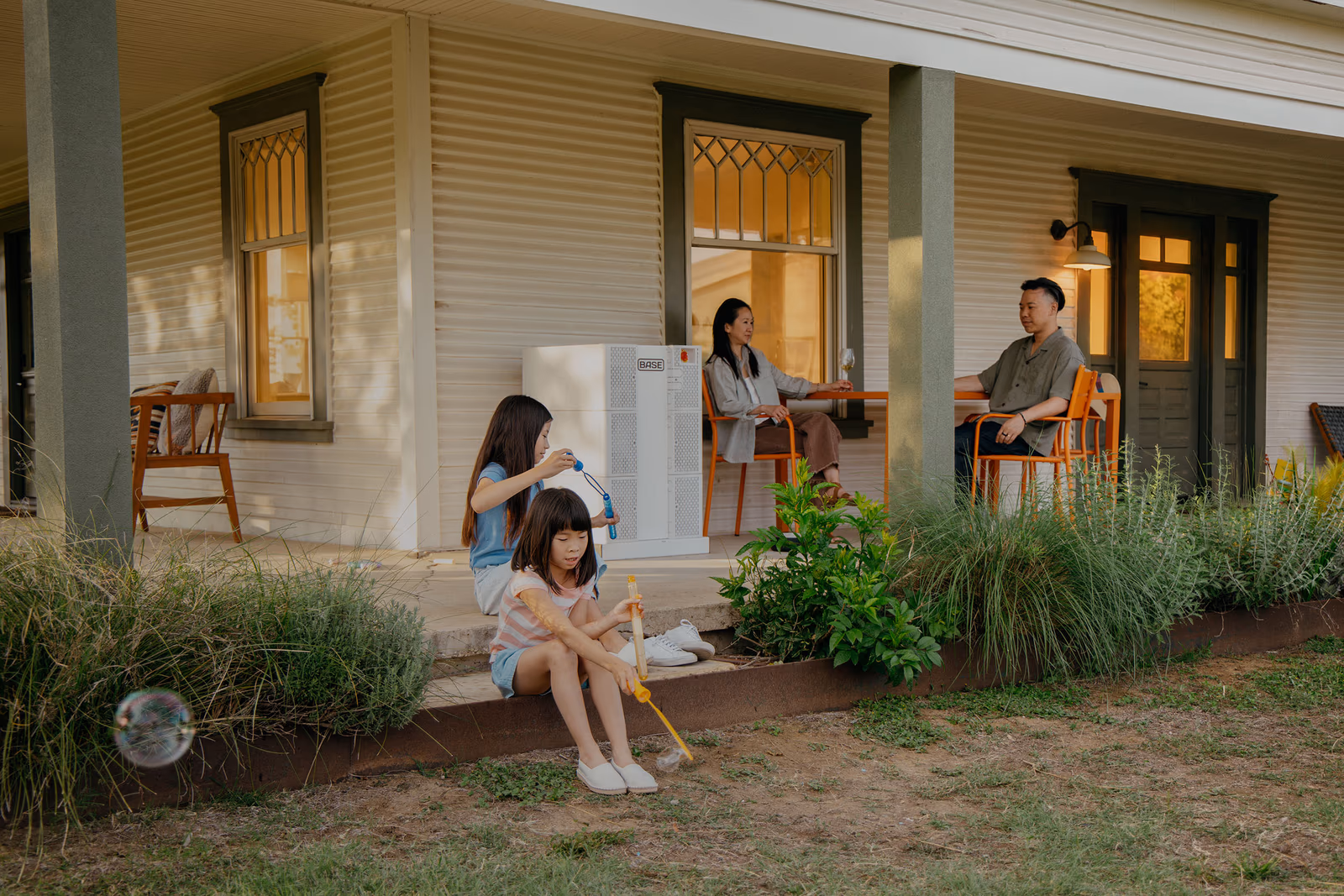 A family relaxing outside their Oncor-served home with a Base Power battery