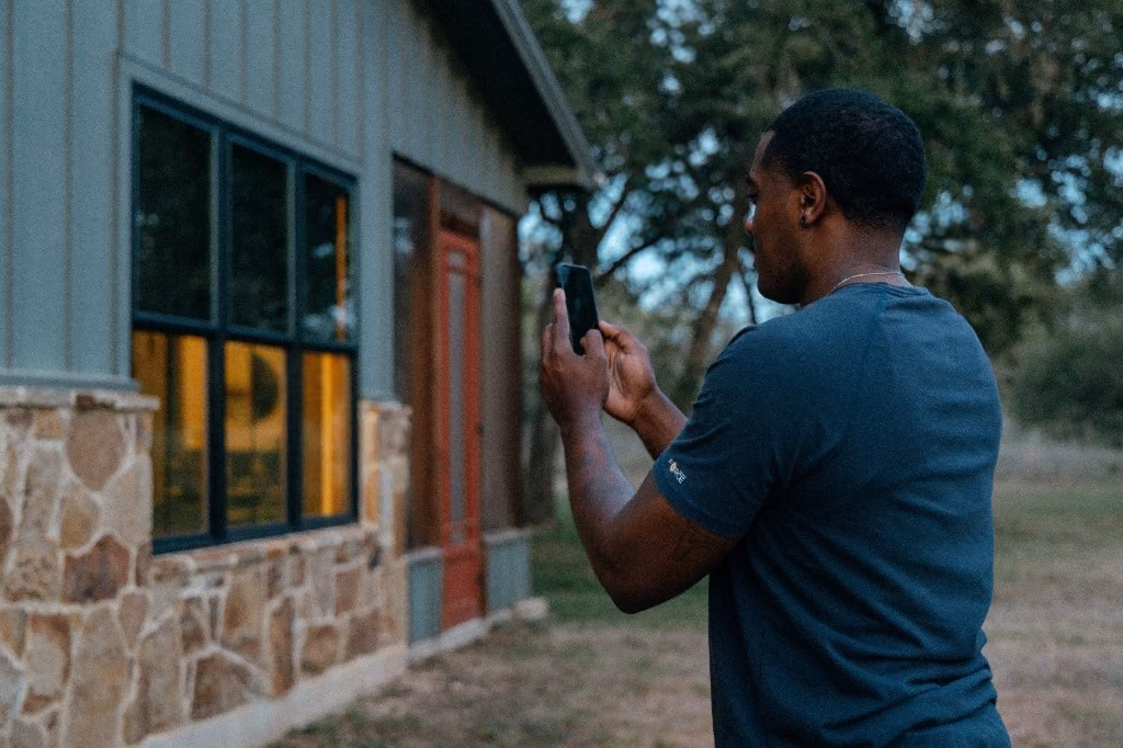 A person photographing their home with a smartphone