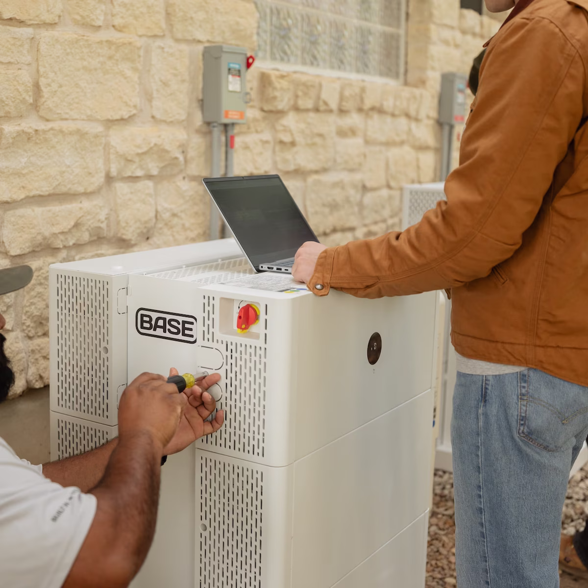 A technician servicing a Base home battery