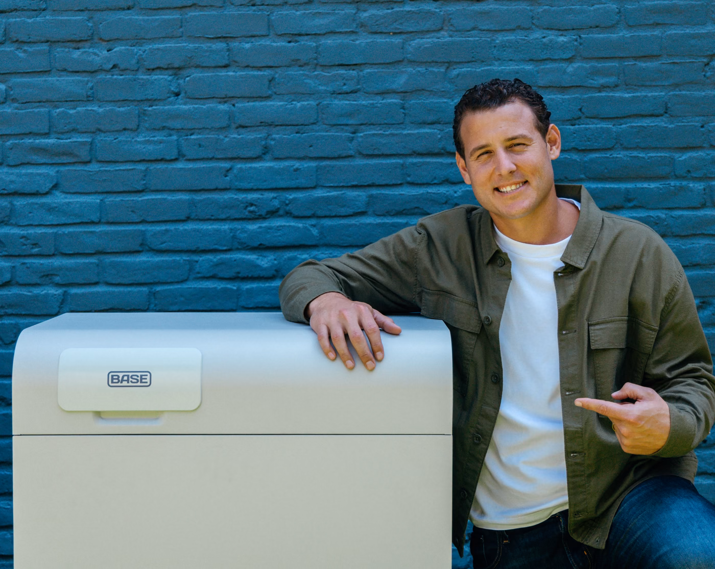 Anthony Rizzo kneeling beside a Base battery, pointing at it